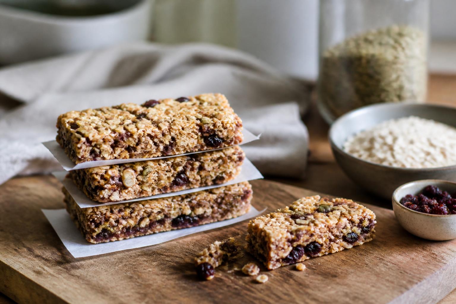 Homemade granola bars topped with nuts and dried fruit arranged on a rustic wooden surface