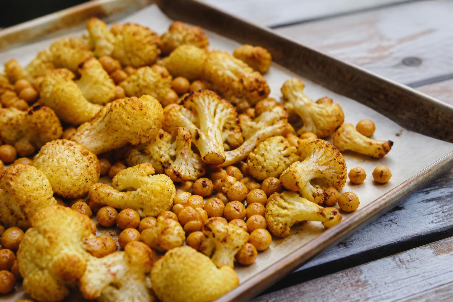 Golden roasted cauliflower florets and crispy chickpeas arranged on a dark ceramic plate