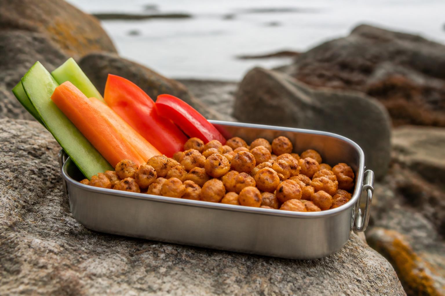 Assorted nuts, dried fruit, and crackers arranged on a wooden desk next to a laptop