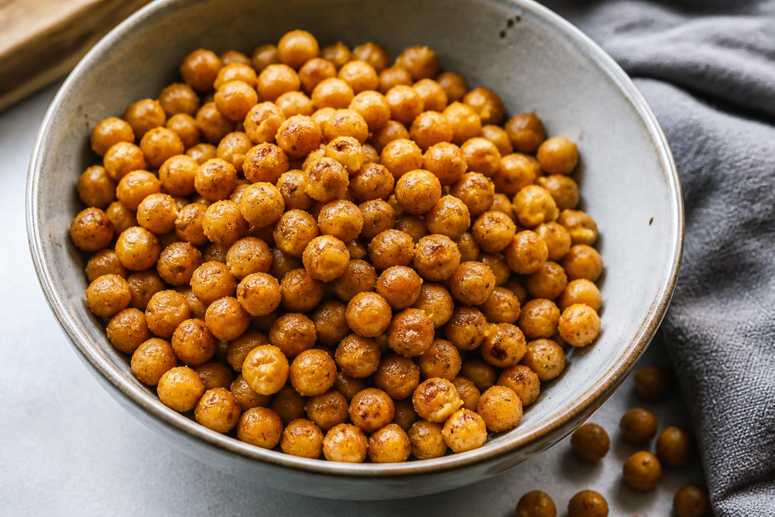 A wooden bowl filled with almonds, chickpeas, and edamame sits on a rustic kitchen counter
