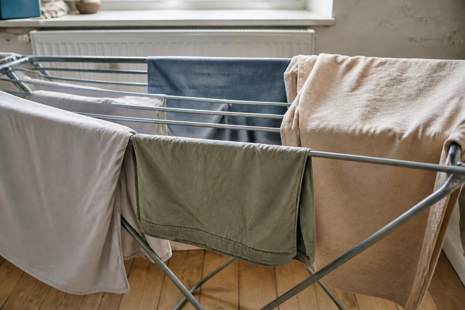 A pile of freshly laundered white towels resting on a wooden surface in a bright, airy room