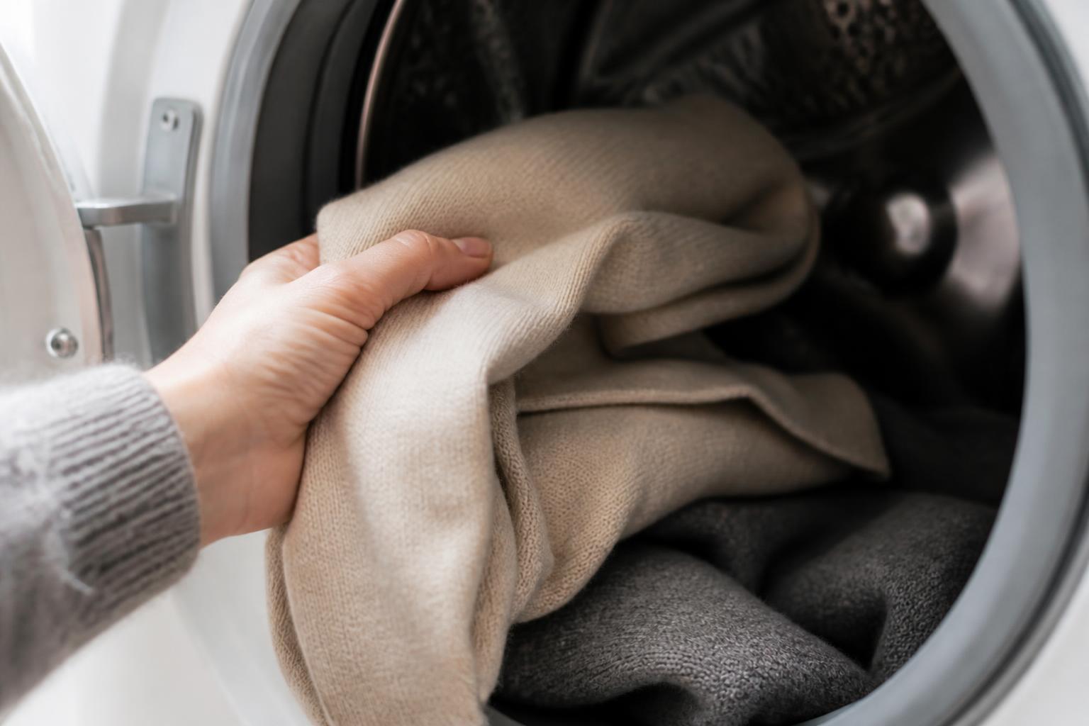 A soft, folded pile of grey merino wool sweaters resting on a clean wooden surface