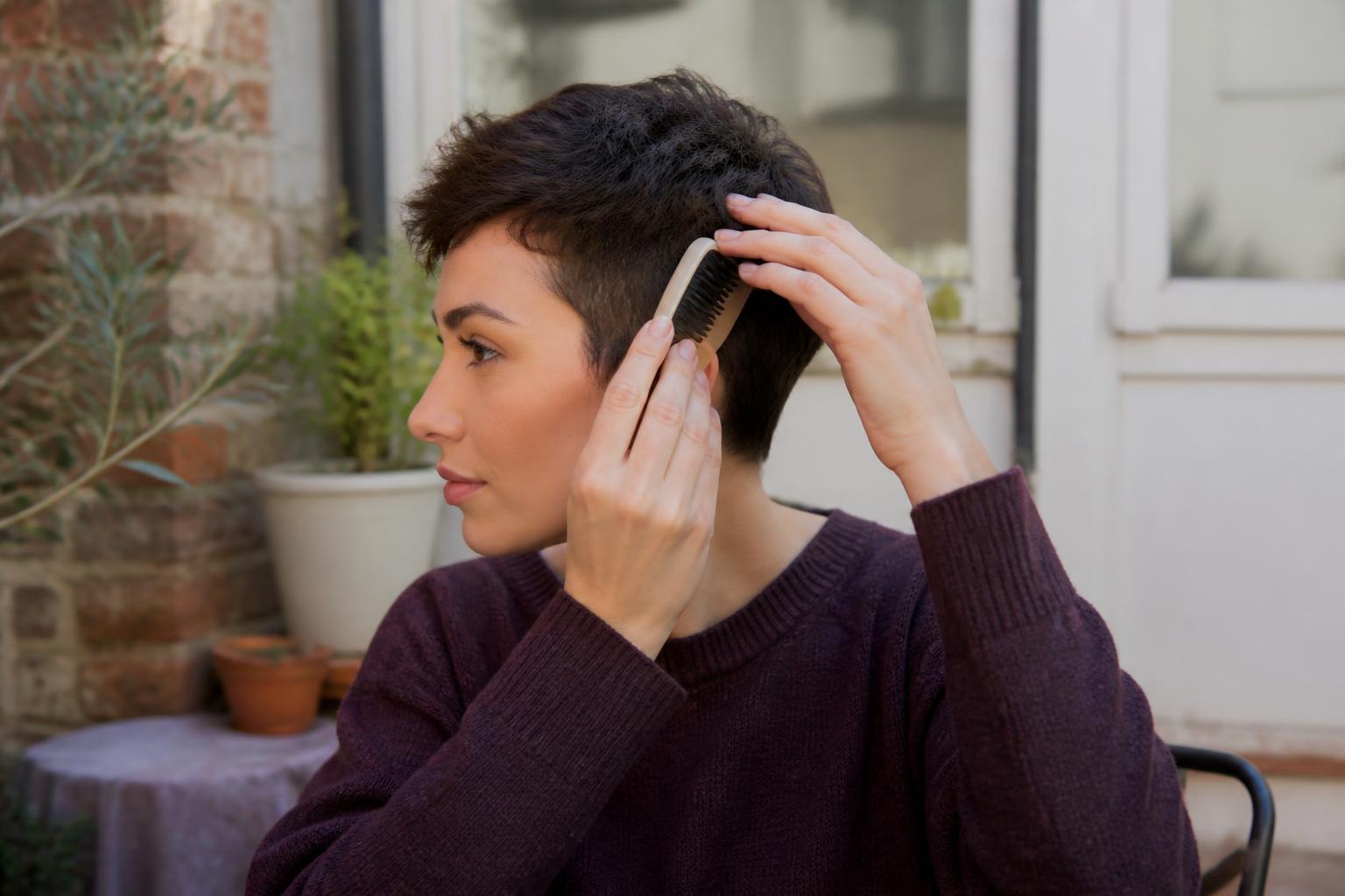 A selection of compact hair styling tools, including a mini straightener and small brushes, on a white surface